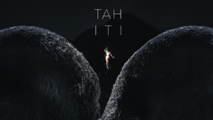Aerial photograph of a person between waves on black sand at Lafayette Beach in Tahiti